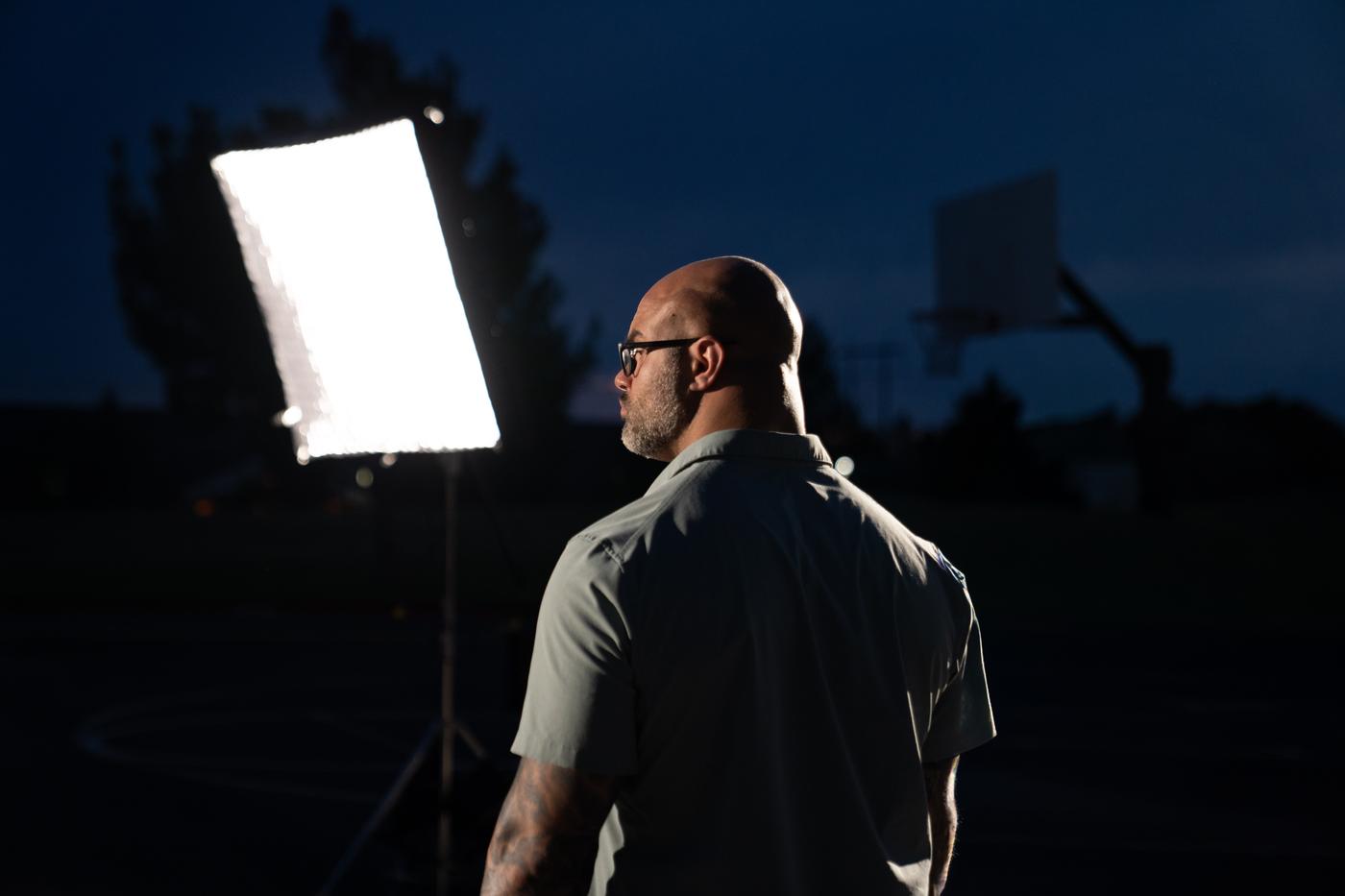 Jason on location beside a film light at dusk